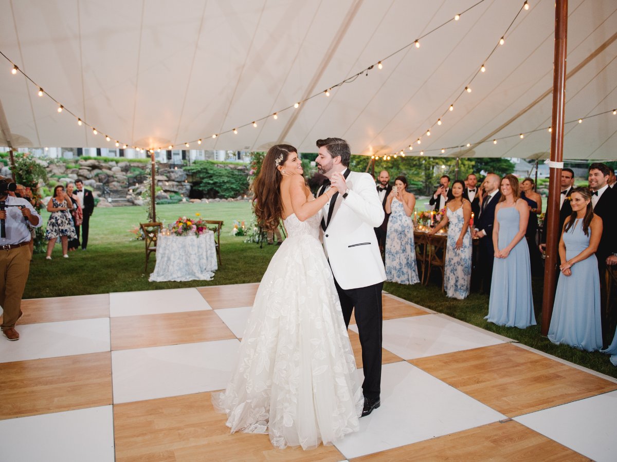 Bride and groom sharing a first dance on a wood and white checkered dance floor at an Oklahoma City tented reception